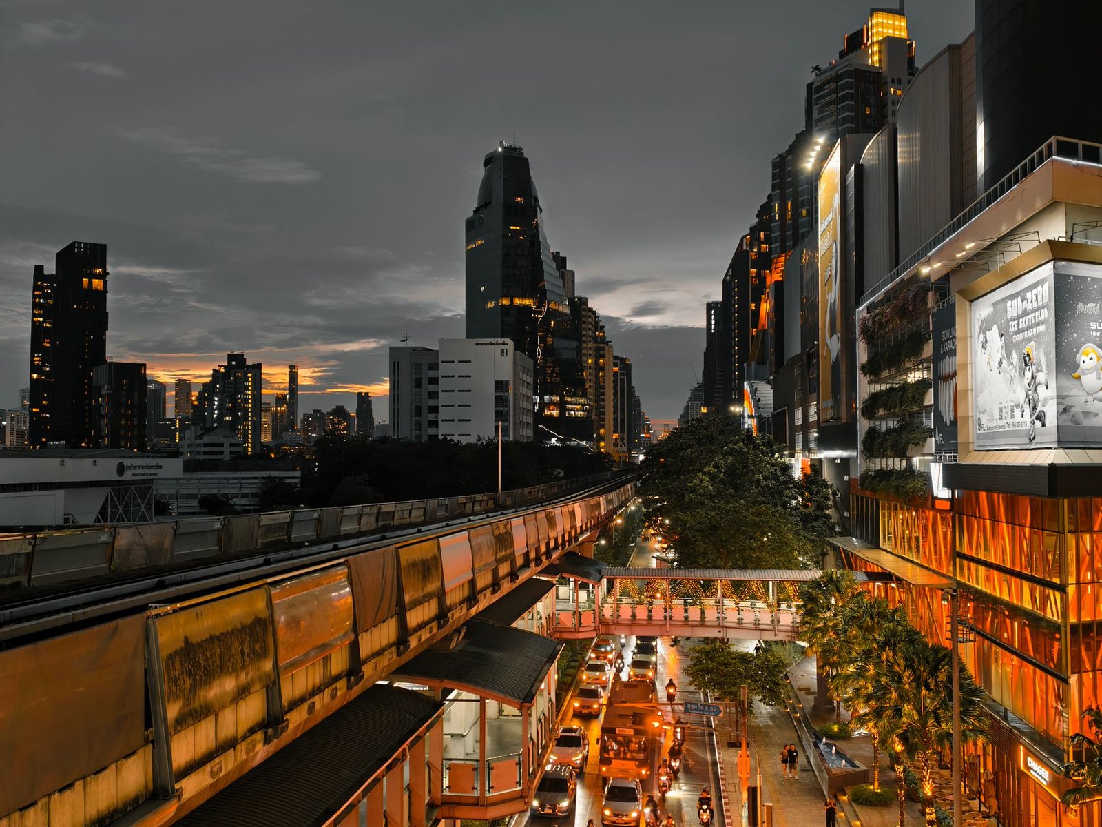 Cityscape at twilight showing busy traffic, skyscrapers, and an elevated train line in an urban setting. — "MetaTrader 4 Andr