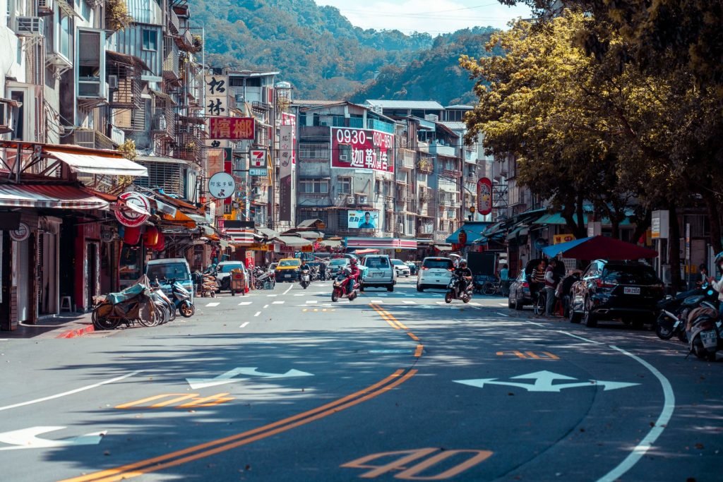 Vibrant urban street scene with shops, vehicles, and mountains in an Asian city. — "Puerto Rico Real Estate: Enjoy Beachfront