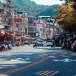 Vibrant urban street scene with shops, vehicles, and mountains in an Asian city. — "Puerto Rico Real Estate: Enjoy Beachfront
