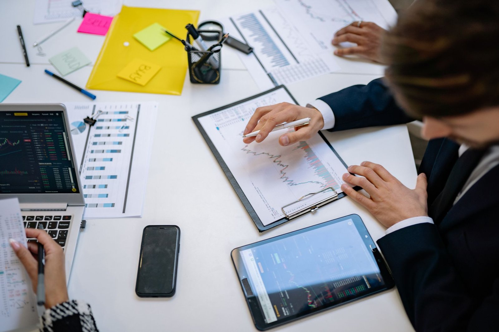 Team reviewing financial charts and digital data on tablets in an office setting. — Request AL Renters Insurance Quotes for F